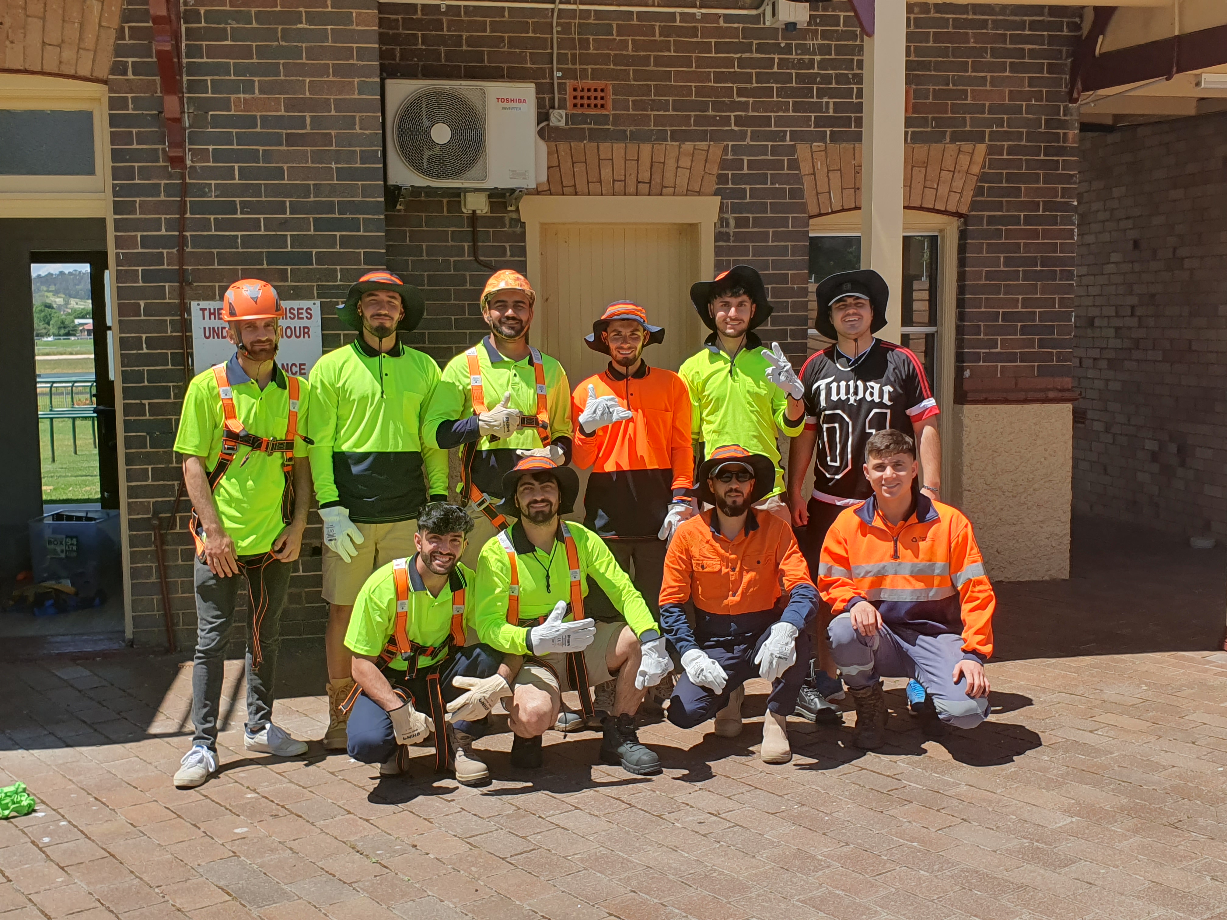 A group of HARVEST participants in high-visibility workwear standing together outside a worksite in Armidale