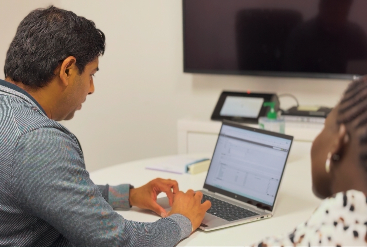 Caseworker working through job applications on a laptop with Akol beside him at Mosaic's Armidale office