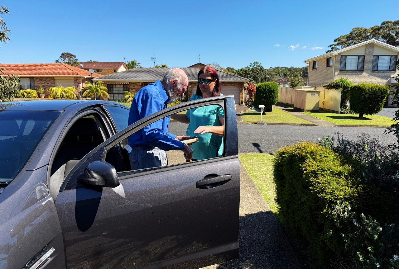 Support worker Kiri helping John Bell out of the car after a grocery shopping trip