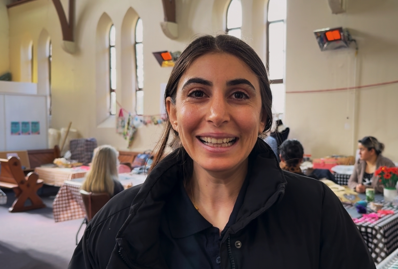 Orien Khalaf smiling inside the Thread Shed community hall, Newcastle