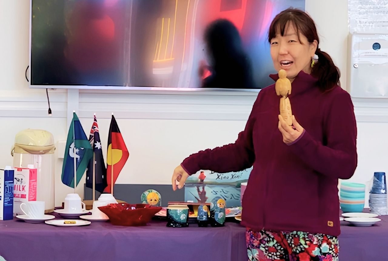 Sumie presenting Japanese cultural items alongside Aboriginal, Torres Strait Islander and Australian flags